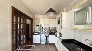 Interior da cozinha com armários brancos e bancada escura.