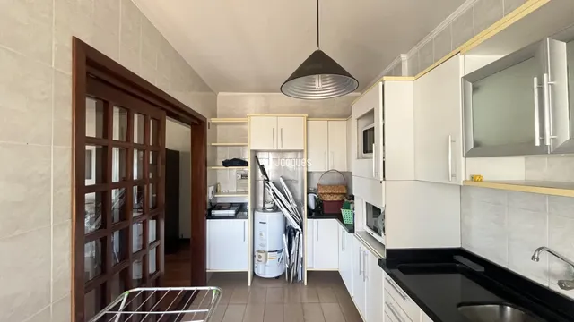 Interior da cozinha com armários brancos e bancada escura.