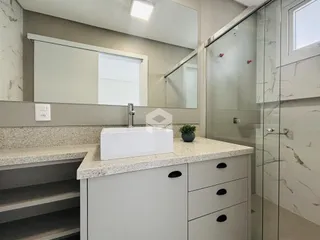 Banheiro com bancada e box de vidro transparente.