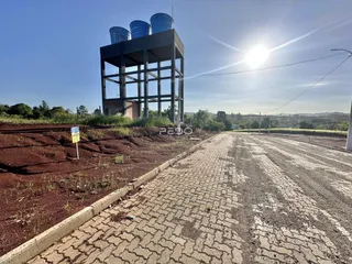 Vista externa de um terreno com uma estrutura industrial ao fundo.