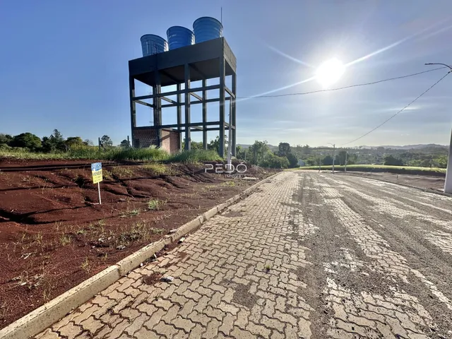 Vista externa de um terreno com uma estrutura industrial ao fundo.