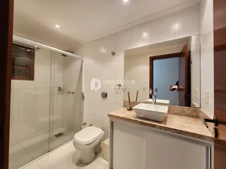 Banheiro com box de vidro e pia de mármore.