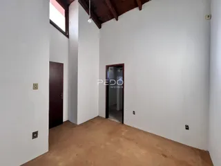 Interior de uma sala com paredes brancas e piso de terra.
