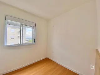 Quarto com piso de madeira e janela de vista para a cidade.
