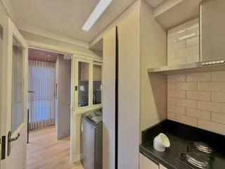 Cozinha com armários brancos e bancada escura.