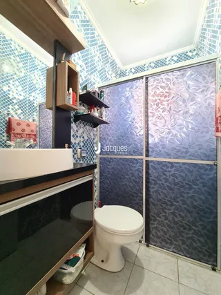 Foto de um banheiro com revestimento de azulejos e bancada de madeira.
