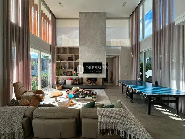 Sala de estar moderna com grandes janelas e lareira em um imóvel no Brasil.