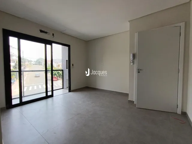 Vista interna de um ambiente com piso de concreto e porta de vidro.