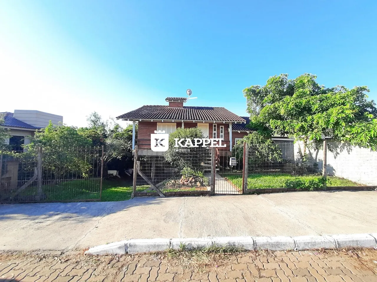 Fachada de uma residência em Lajeado, Brasil, com cerca e vegetação ao redor.