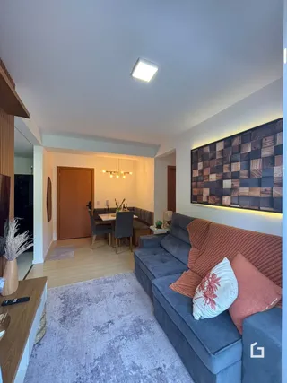 Sala de estar com sofá cinza e piso de madeira clara.