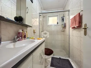Foto de um banheiro com box de vidro e revestimento cerâmico nas paredes.