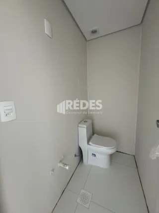 A foto mostra um corredor com um vaso sanitário branco.