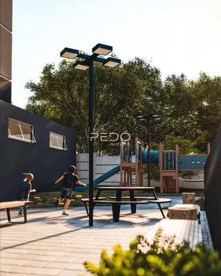 Área externa pavimentada com playground e árvores em Lajeado.