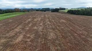 Vista aérea de um campo aberto com vegetação rasteira e colinas ao fundo.