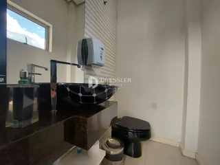 Vista da área de banheiro com bancada escura e vaso sanitário preto.