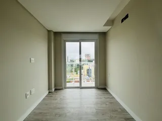 Corredor interno com piso de madeira clara e porta de vidro.