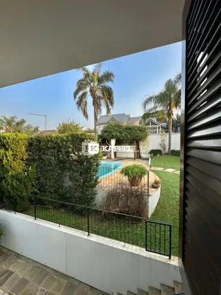 Vista externa mostrando uma área de jardim com piscina e vegetação.