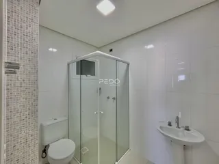 Foto interna de um banheiro com revestimento cerâmico e box de vidro.