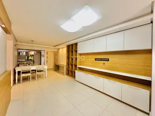 Ambiente interno de uma sala de estar com armários brancos e detalhes em madeira.