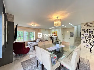 Sala de estar com mesa de vidro e sofás brancos.