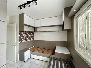 Quarto com cabeceira de madeira e armários brancos em imóvel no Brasil.