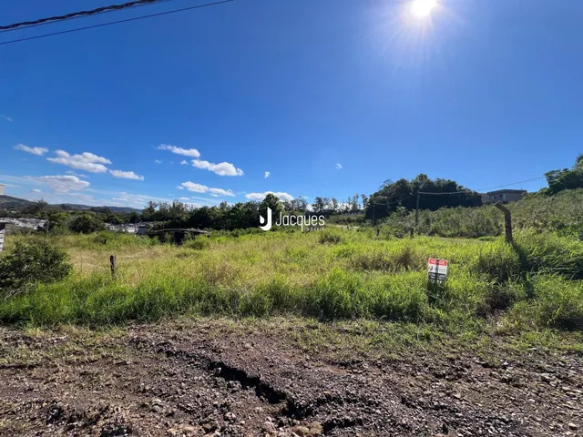 Paisagem de campo com vegetação e terra sob um céu azul claro.