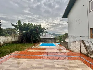 Vista externa de uma propriedade com piscina e muro.