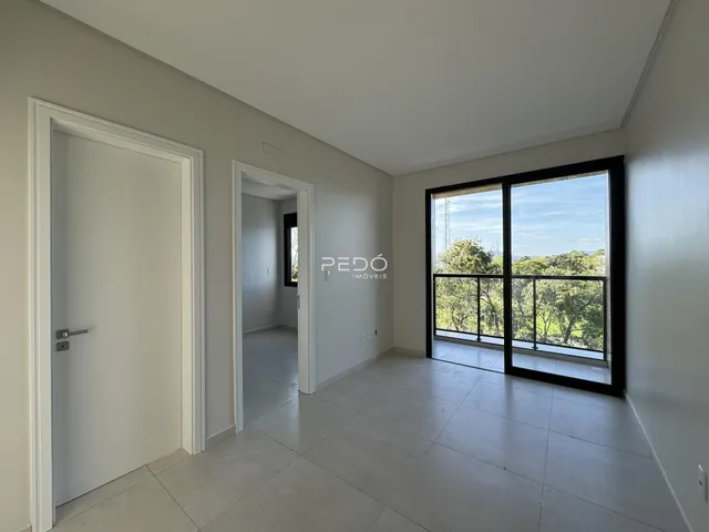 Interior de uma sala com porta de entrada e vista para o exterior.