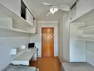Ambiente interno com paredes brancas e piso de madeira clara.