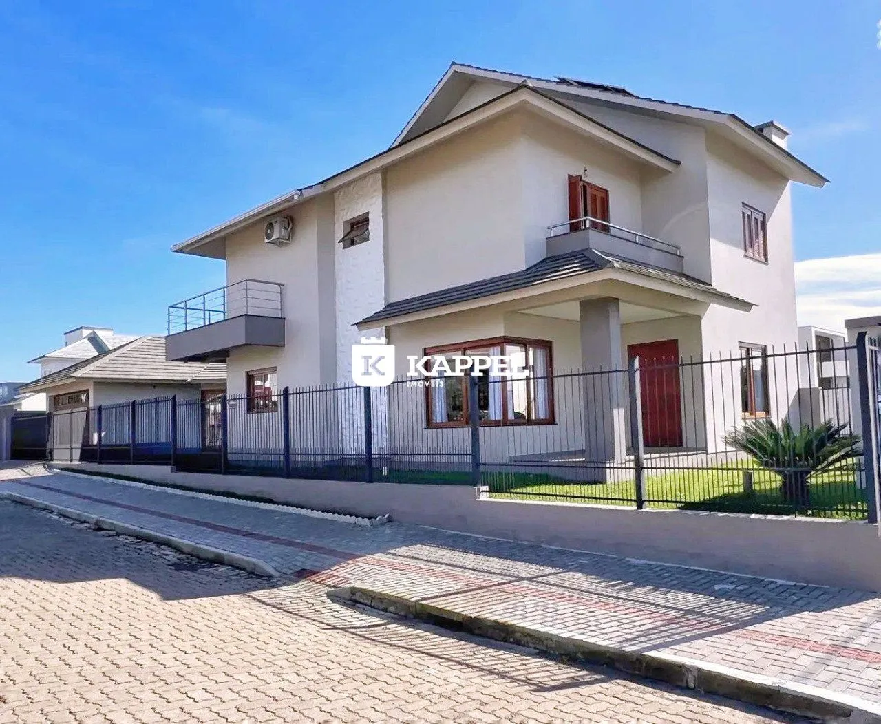 Fachada de uma casa branca de dois andares com cerca frontal.
