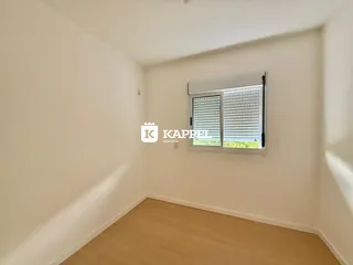 Vista interna de um cômodo com piso de madeira e janela com persiana.