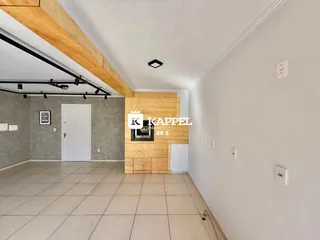 Sala de estar com piso de cerâmica e lareira de madeira em um ambiente claro.