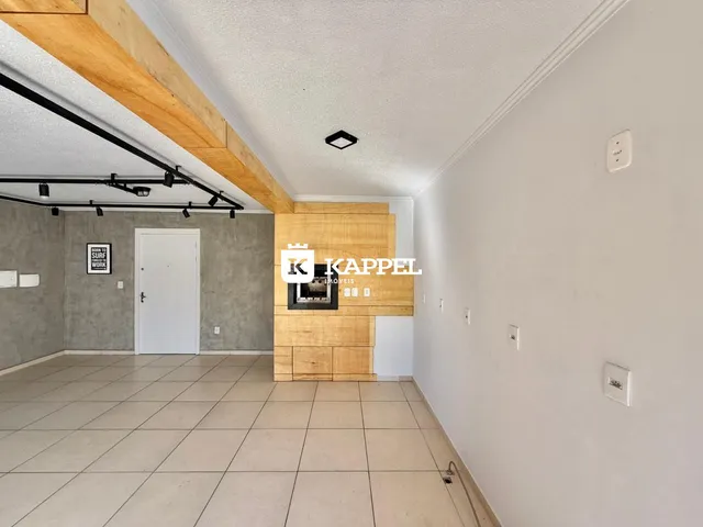 Sala de estar com piso de cerâmica e lareira de madeira em um ambiente claro.