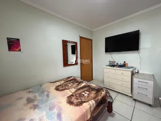 A foto mostra o interior de um quarto com cama e televisão.