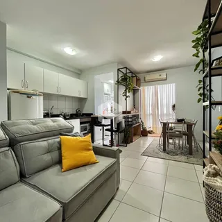 Sala de estar com sofá e cozinha em apartamento.