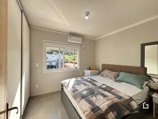 Quarto com cama e janela em ambiente claro.