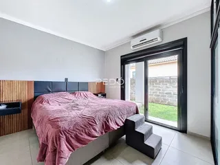Quarto com cama e porta de vidro de acesso ao exterior.