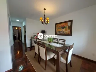 Uma sala de jantar com mesa de madeira escura e lustre.
