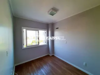Sala de estar com piso de madeira e janela voltada para a paisagem.