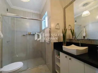 Foto do interior de um banheiro com box de vidro e louças sanitárias.