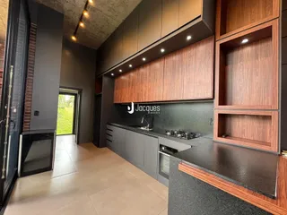 Uma cozinha moderna com armários de madeira escura e bancadas pretas.
