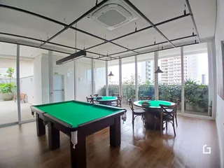 Ambiente interno com mesa de bilhar e grandes janelas.