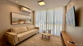 Sala de estar com sofá e cortinas claras.