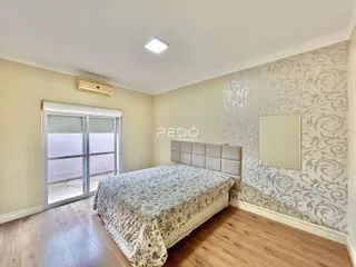 Quarto com cama e piso de madeira clara em um imóvel no Brasil.