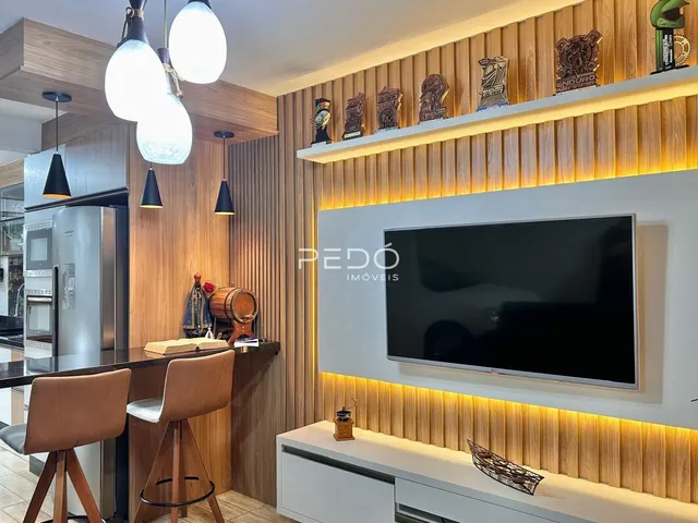 Ambiente moderno com painel de madeira e televisão na sala de estar.