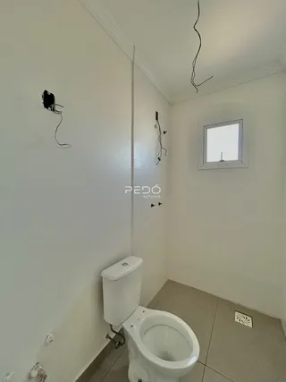 A foto mostra o interior de um banheiro com piso de cerâmica e paredes brancas.
