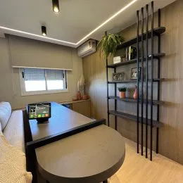 Foto de uma sala de estar com mesa grande e estante de livros.