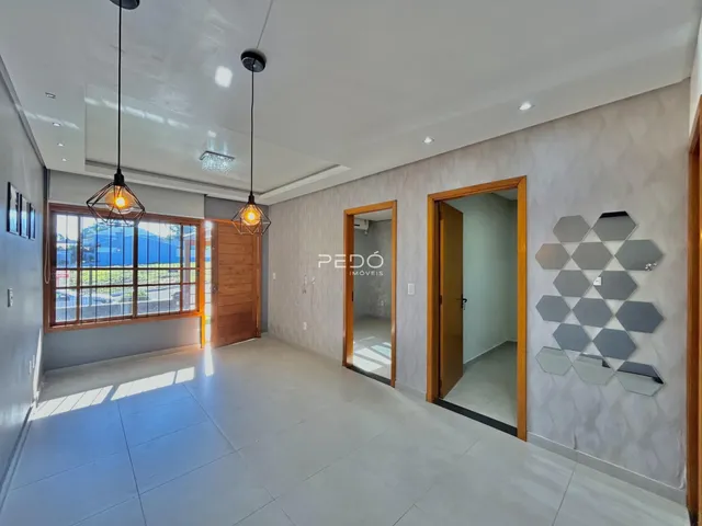 Interior de uma sala de estar ampla com piso claro e portas de madeira.