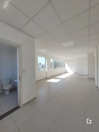 Corredor interno de um imóvel com paredes brancas e piso de cerâmica.