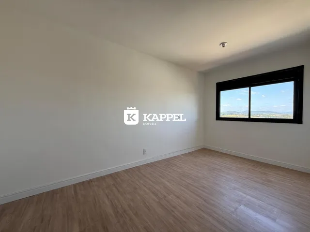 Vista interna de um cômodo com piso de madeira e janela para a paisagem.